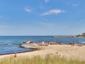 Ein Strand mit Menschen, Booten und einem Gebäude im Hintergrund.
