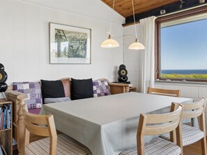 Ein Essbereich mit Tisch, Stühlen, einer Bank und Meerblick.