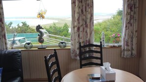 A room with a view of a landscape, a table with a tissue box, and a chair. - Donegal Mobile Home-coast-family Friendly-sleeps 5 (Gortahork)