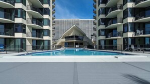 A swimming pool surrounded by multi-story buildings with balconies. - Coastal Bliss Beachfront Resort Oasis for 5! (Panama City Beach)
