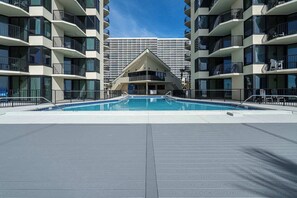 A swimming pool surrounded by multi-story buildings with balconies. - Coastal Bliss Beachfront Resort Oasis for 5! (Panama City Beach)