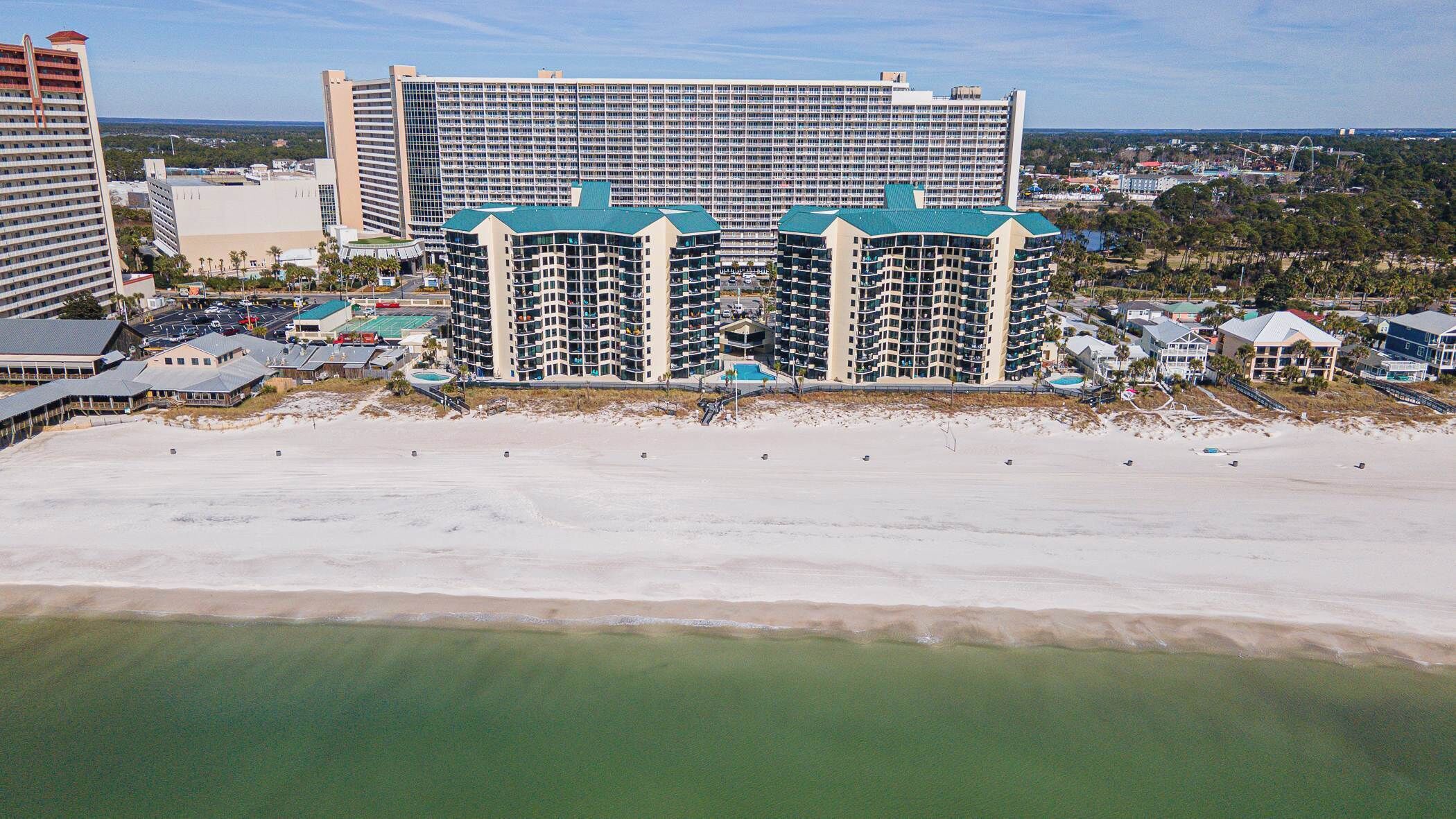 A beachfront hotel with multiple high-rise buildings, a sandy beach, and a clear view of the ocean.