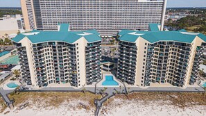 A high-rise hotel with multiple balconies, a central swimming pool, and a beach view. - Coastal Bliss Beachfront Resort Oasis for 5! (Panama City Beach)