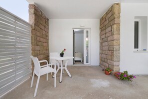 A small patio with a table and chairs, a potted plant, and a view into the house. - Villa Matilde Domo Boutique - Barby Room (Torre degli Ulivi)