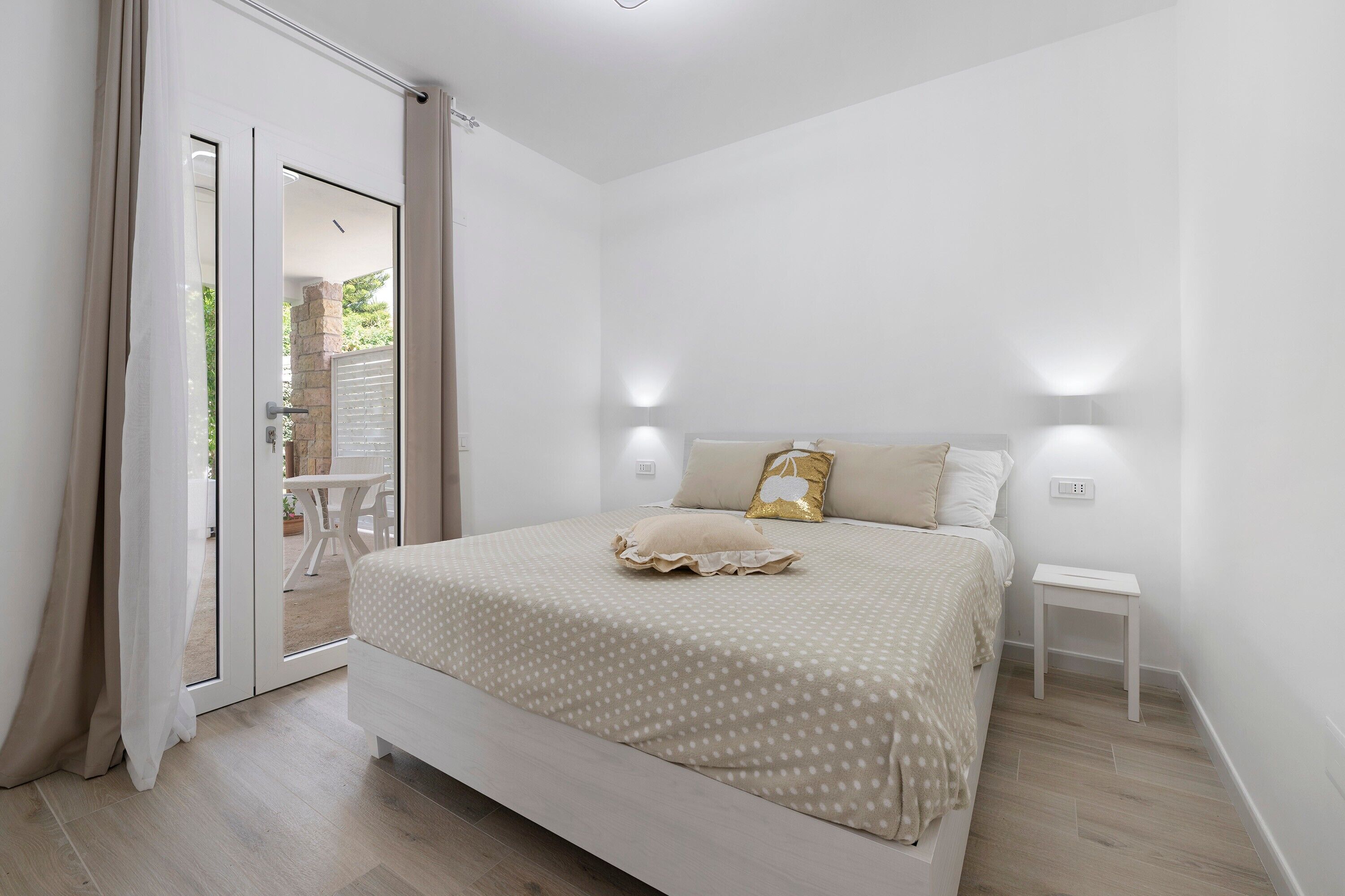 Een slaapkamer met een bed, nachtkastje en een schuifdeur naar een buitenruimte.