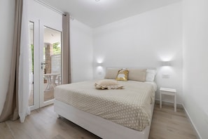 Ein Schlafzimmer mit einem Bett, einem Nachttisch und einer Schiebetür zu einem Außenbereich.