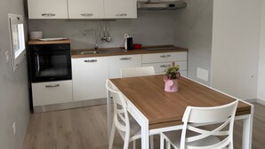 Uma cozinha moderna com armários brancos, uma mesa de jantar de madeira e cadeiras brancas.