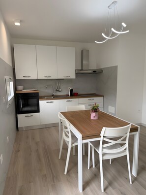 Eine moderne Küche mit weißen Schränken, einem Holztisch und weißen Stühlen.