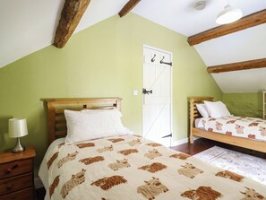 A bedroom with two beds, a wooden headboard, a white door, and a lamp on a nightstand. - Frondirion (Machynlleth)