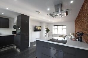 A modern kitchen with dark cabinetry, a central island, and a built-in oven. - Cozy corner - Perfect retreat only 10 minutes Walk to the Marina and Old Town (Kingston upon Hull)