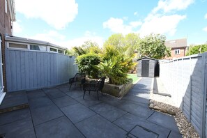 A backyard patio with a grey fence, two black chairs, a small garden with plants, and a shed. - Cozy corner - Perfect retreat only 10 minutes Walk to the Marina and Old Town (Kingston upon Hull)