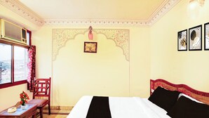 Une chambre à coucher avec un lit, une chaise, une table et une fenêtre avec des rideaux.