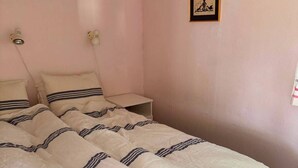 A bedroom with a bed, bedside tables, a wall-mounted light, and a framed picture.
