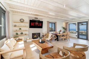 Een moderne woonkamer met een open haard, een grote flatscreen-tv en een eethoek met uitzicht.