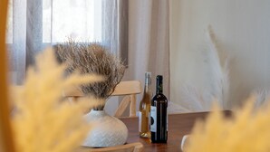 Ein Esstisch mit zwei Flaschen, einer Vase mit Trockenpflanzen und einem Stuhl.