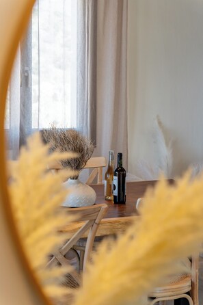 Ein Esstisch mit zwei Flaschen, einer Vase mit Trockenpflanzen und einem Stuhl.