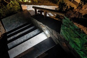 Eine Treppe aus Stein, die zu einem hölzernen Geländer führt, umgeben von Grünpflanzen.