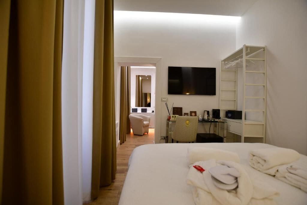 A hotel room with a bed, a desk, a TV, and a wardrobe.