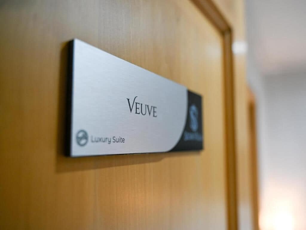 A sign on a wooden door indicating a 'Luxury Suite' named 'VEUVE'.
