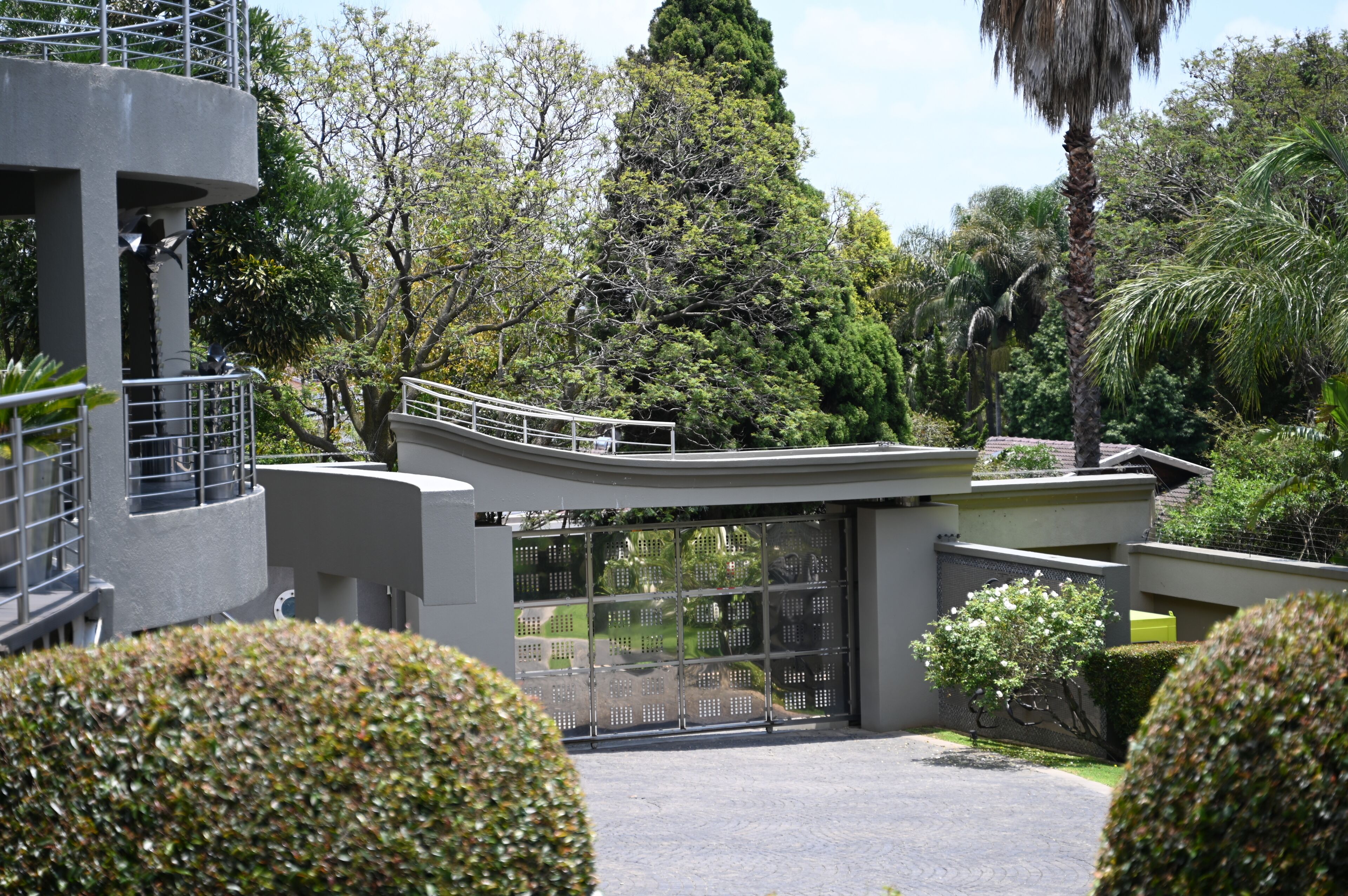 Un edificio moderno con techo curvo, rodeado de abundante vegetación y árboles.