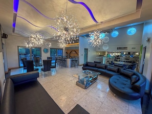 A modern living room with a large sofa, a coffee table, and a dining area with chairs.