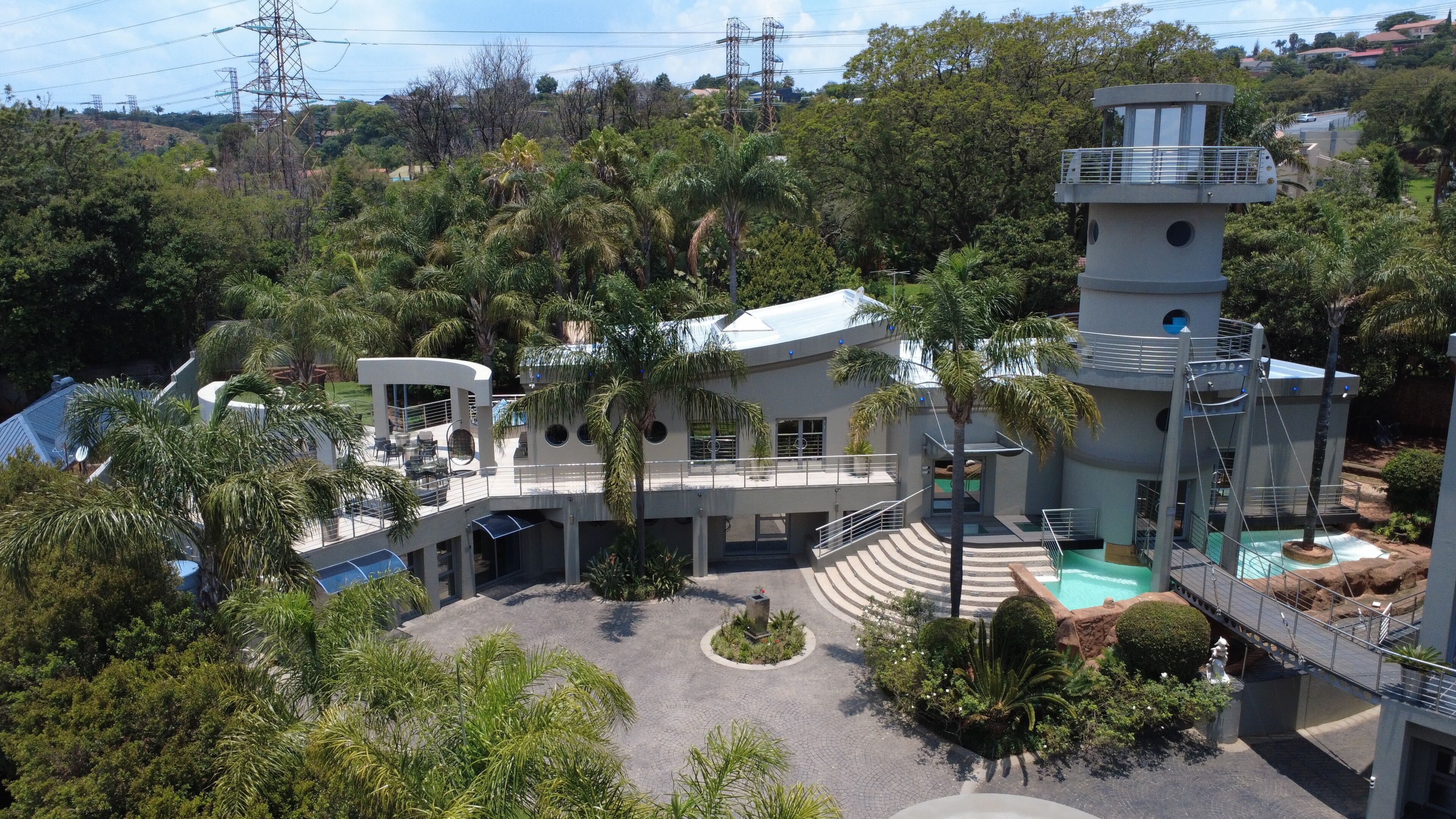 A modern building with multiple levels, a swimming pool, and surrounding greenery.