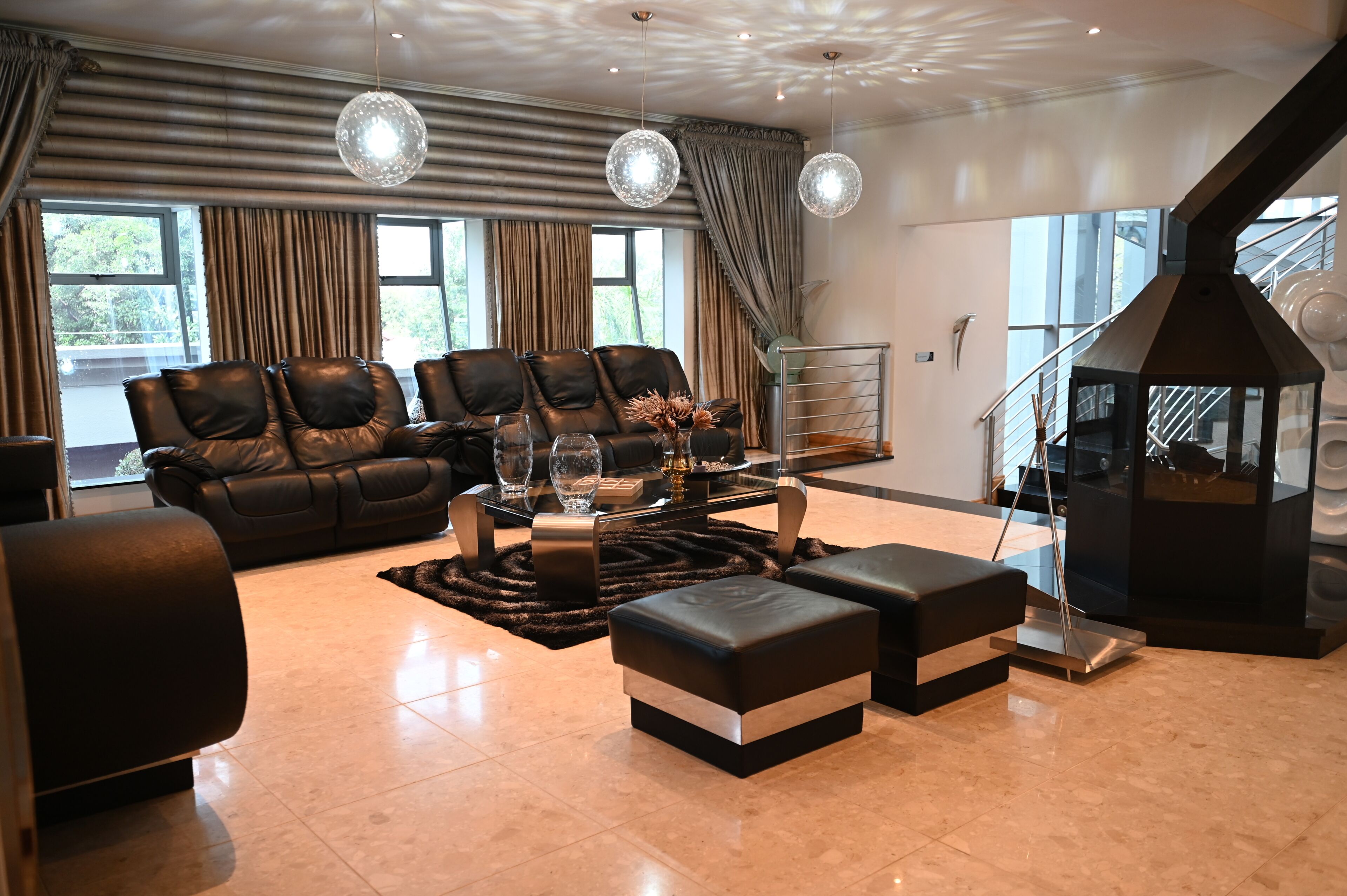 Ein modernes Wohnzimmer mit Ledersofas, einem Glastisch und einem Kamin.