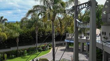 Un edificio moderno con balcón que da a un jardín ajardinado con palmeras.