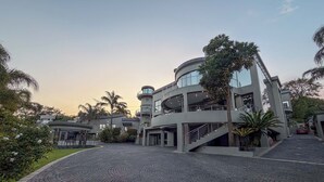 A modern building with a circular tower, a covered walkway, and a paved courtyard.