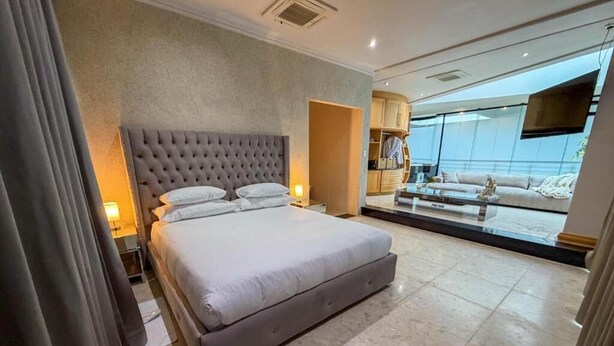 A modern hotel room with a large bed, a flat-screen TV, and a view of the city.