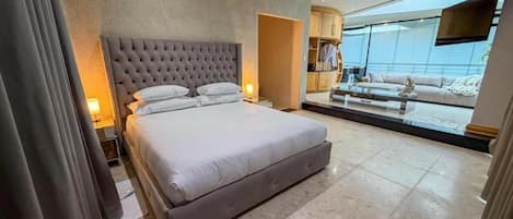A modern hotel room with a large bed, a flat-screen TV, and a view of the city.