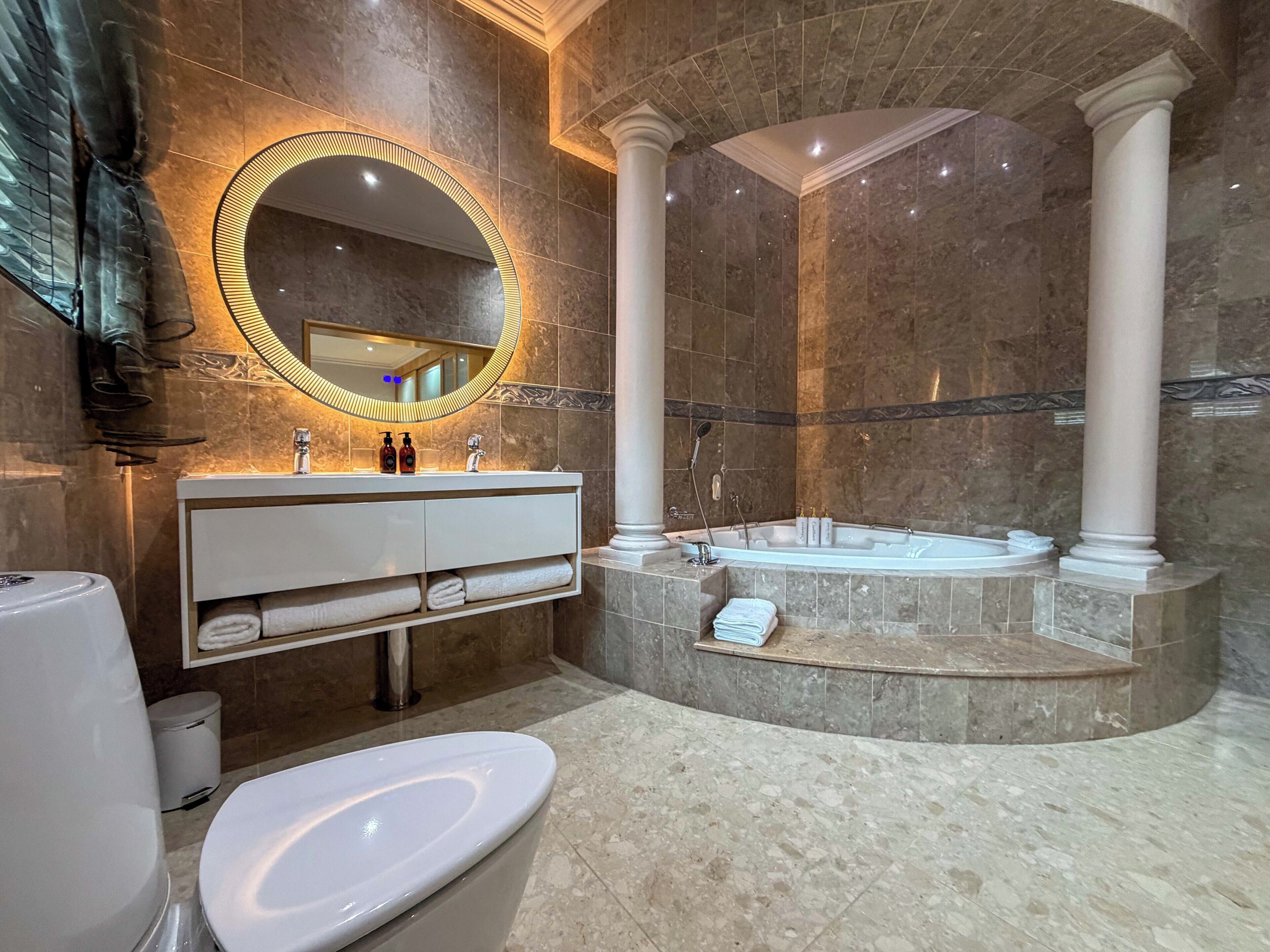 Un baño moderno con una bañera independiente, un tocador con espejo y un inodoro.