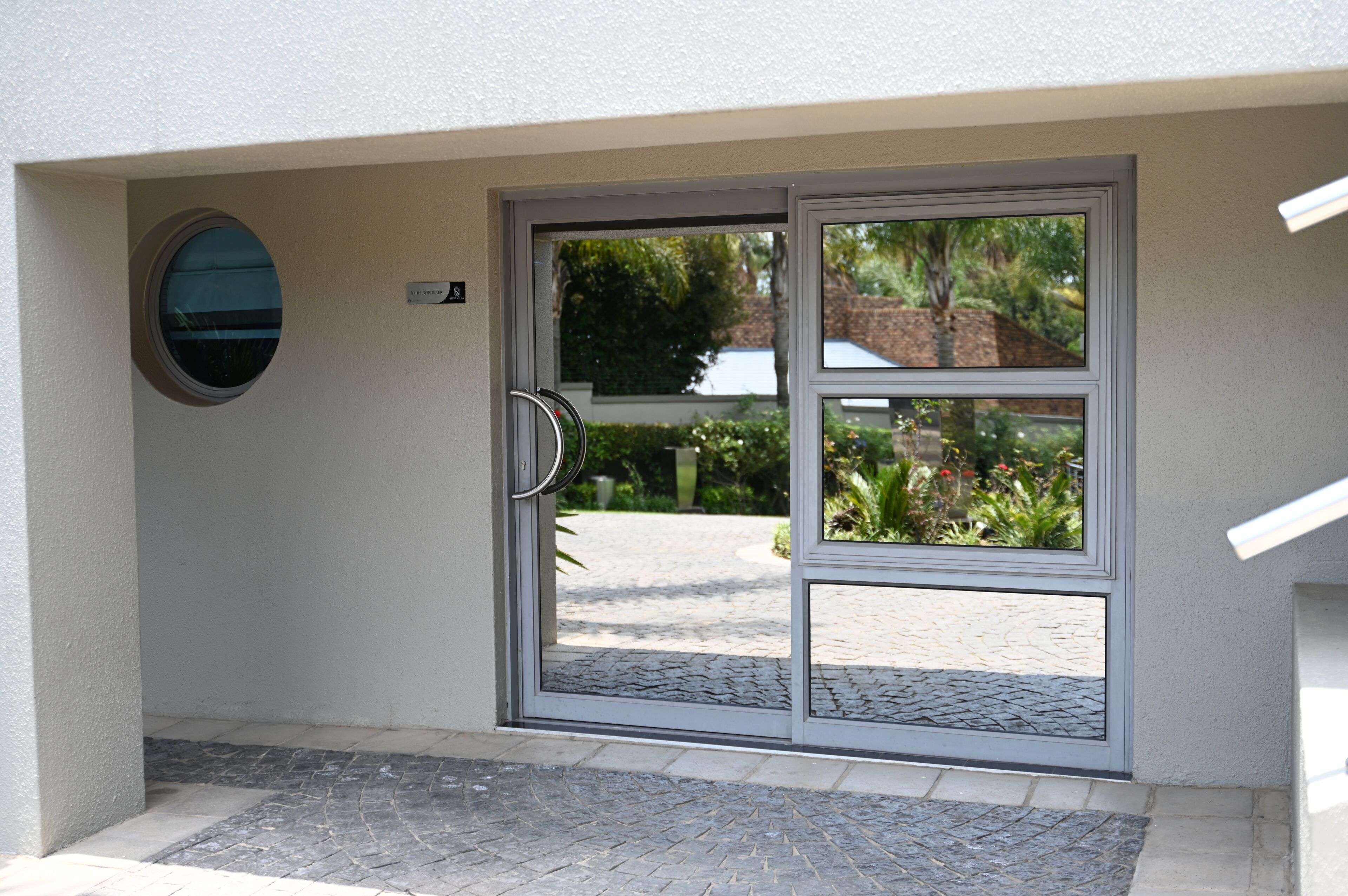 A modern entrance with a glass door, a nameplate, and a small circular window.