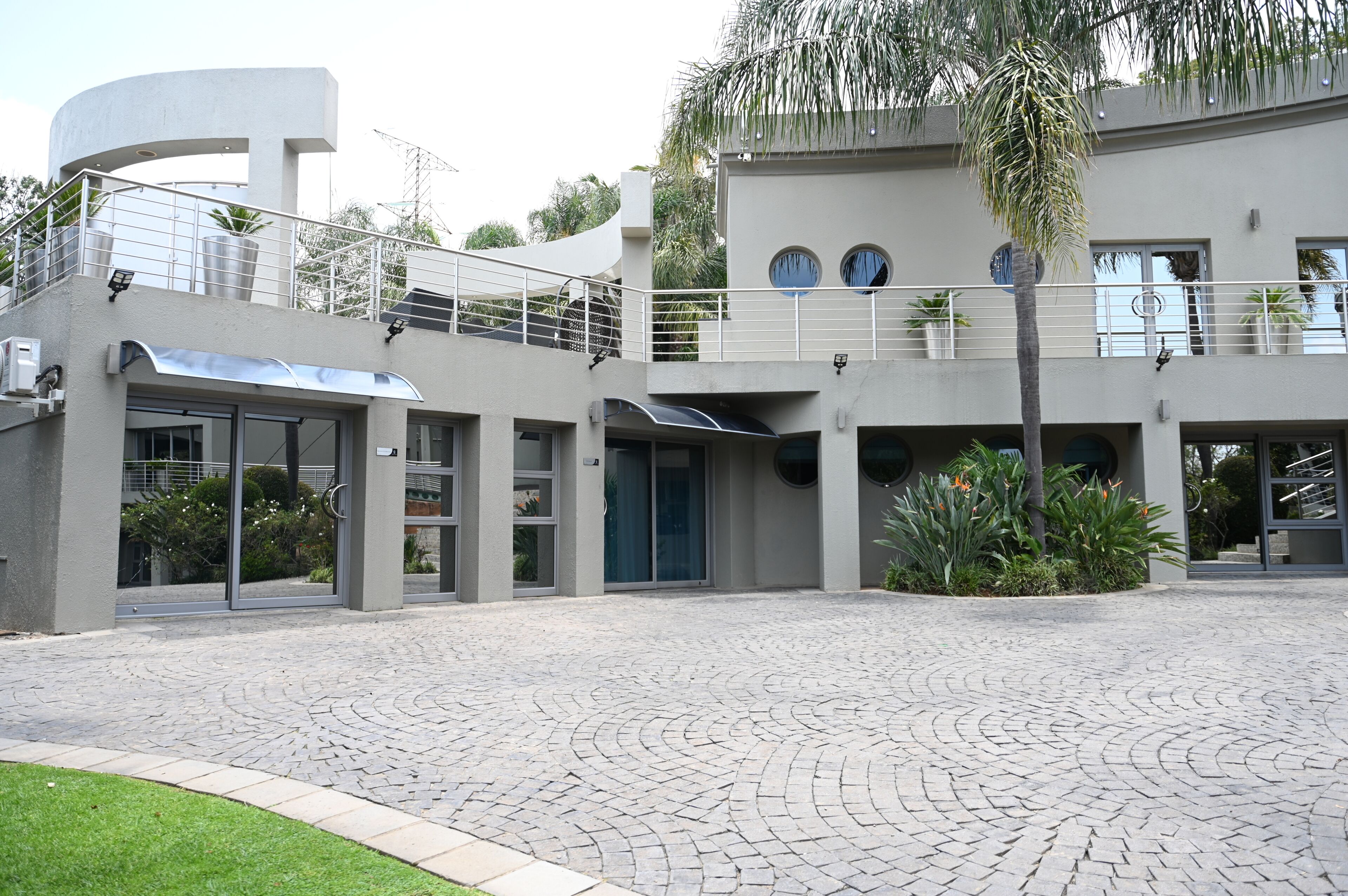 Un edificio moderno con fachada curva, entrada cubierta y patio empedrado.
