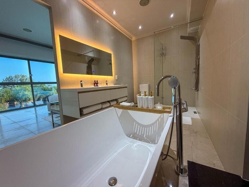 A modern bathroom with a large bathtub, a glass-enclosed shower, and a vanity with a mirror.