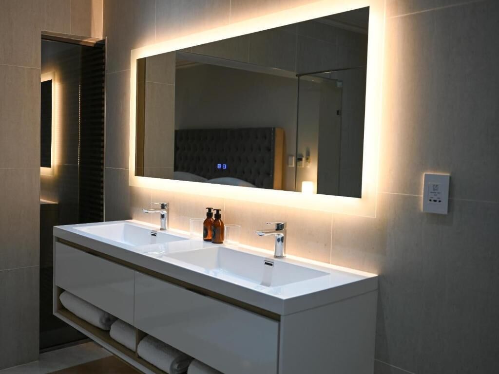 A modern bathroom with a double sink vanity, a large mirror, and a towel rack.