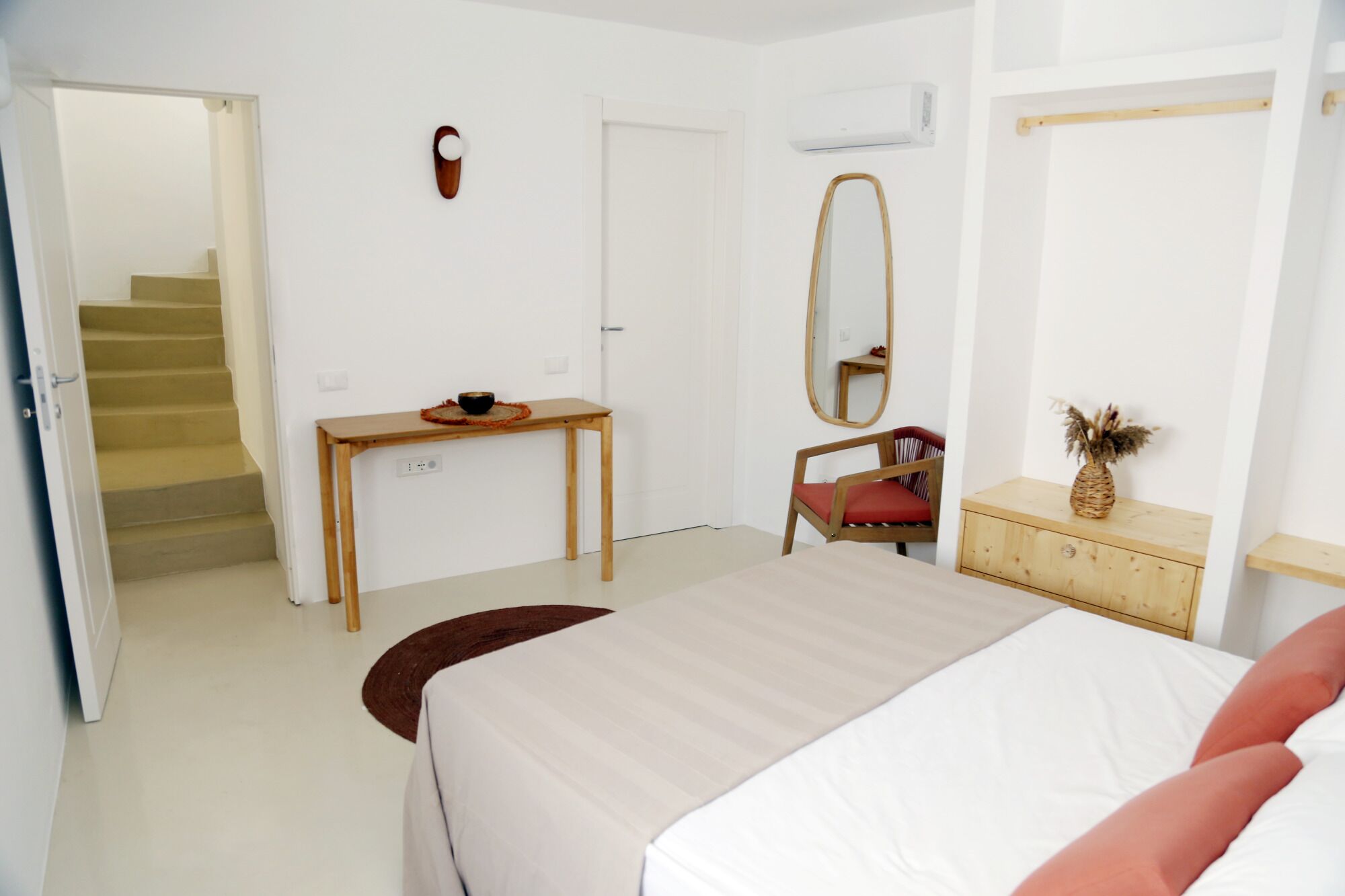 Une chambre à coucher comprenant un lit, un bureau, une chaise, un miroir et une commode.