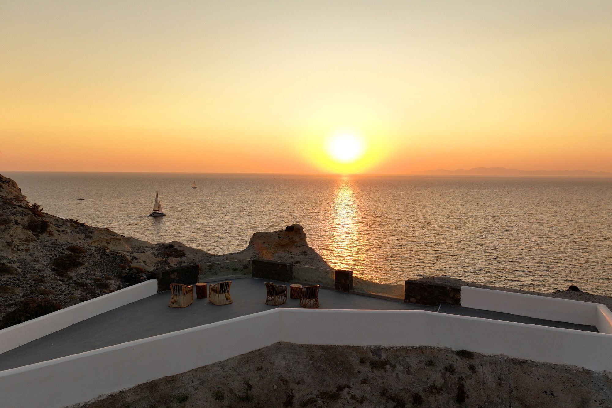 Vista de un atardecer costero con zona de estar frente al mar.