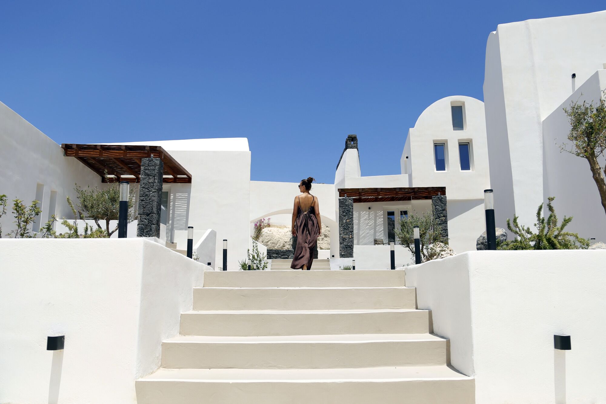 Una persona baja por una escalera blanca en un entorno arquitectónico moderno, con líneas limpias y diseño minimalista.