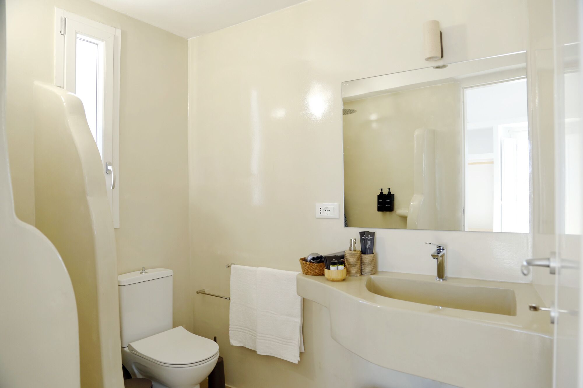A bathroom with a toilet, sink, and mirror.