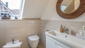 A bathroom with a toilet, sink, and mirror. - Villa 'Ferienhaus Residenz am Vulkanradweg' with Terrace, Garden & Wi-Fi (Grebenhain)