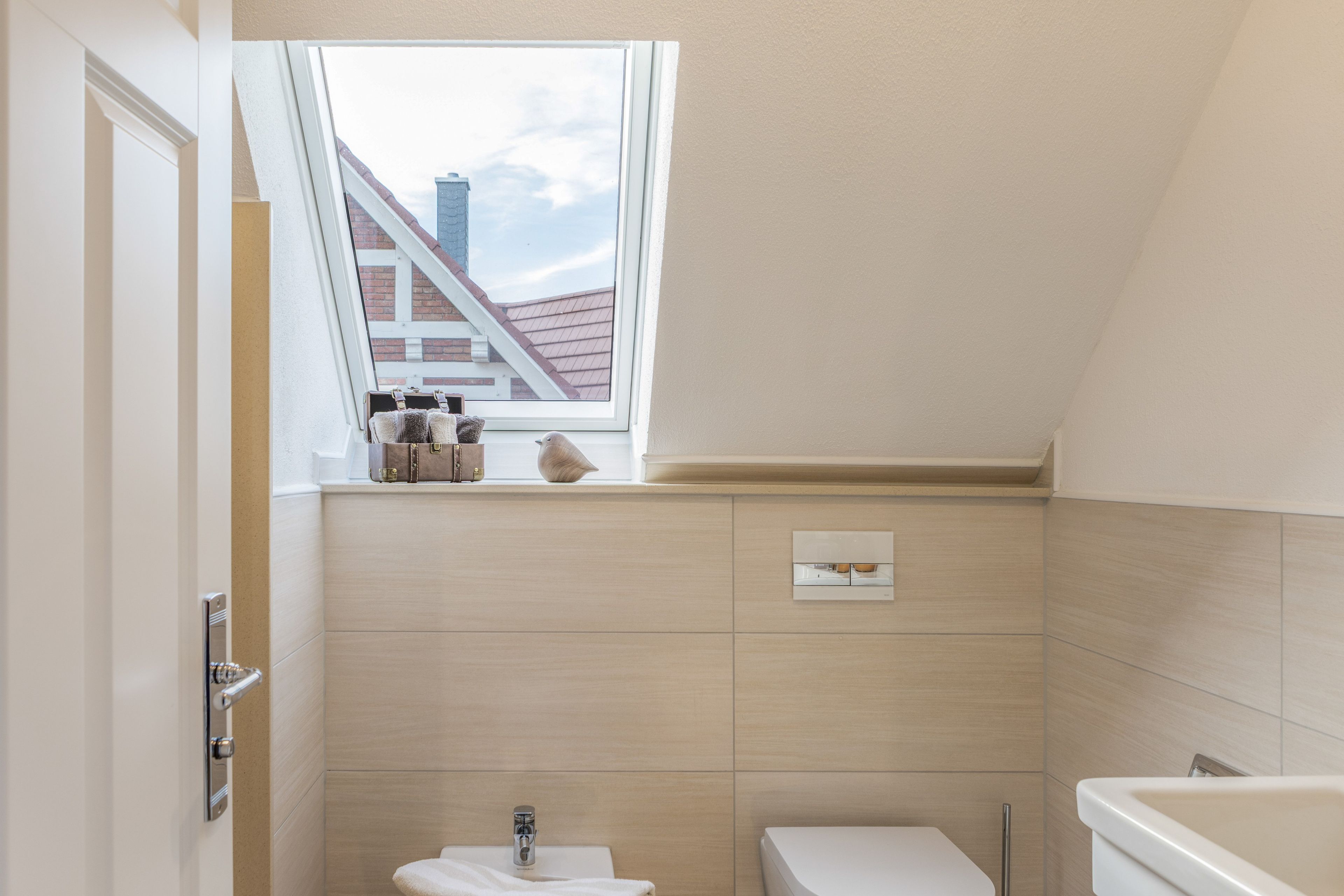 A small, modern bathroom with a skylight, a toilet, and a bathtub.