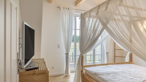 A bedroom with a bed, a TV, and a window with curtains. - Villa 'Ferienhaus Residenz am Vulkanradweg' with Terrace, Garden & Wi-Fi (Grebenhain)