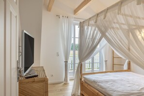 Una camera da letto con un letto, una TV e una finestra con tende.