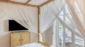 Una habitación con una cama, un televisor sobre un mueble, y una ventana que da al exterior.