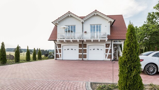 A two-story house with a red roof, white exterior, and a paved driveway. - Villa 'Ferienhaus Residenz am Vulkanradweg' with Terrace, Garden & Wi-Fi (Grebenhain)