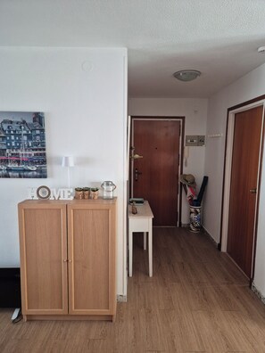 A hallway with a wooden cabinet, a small table, and a door. - Vacation Rental Apartment Near the Beach (VC)