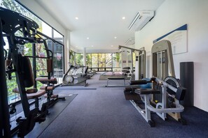 A gym with various exercise equipment, large windows, and an air conditioning unit.