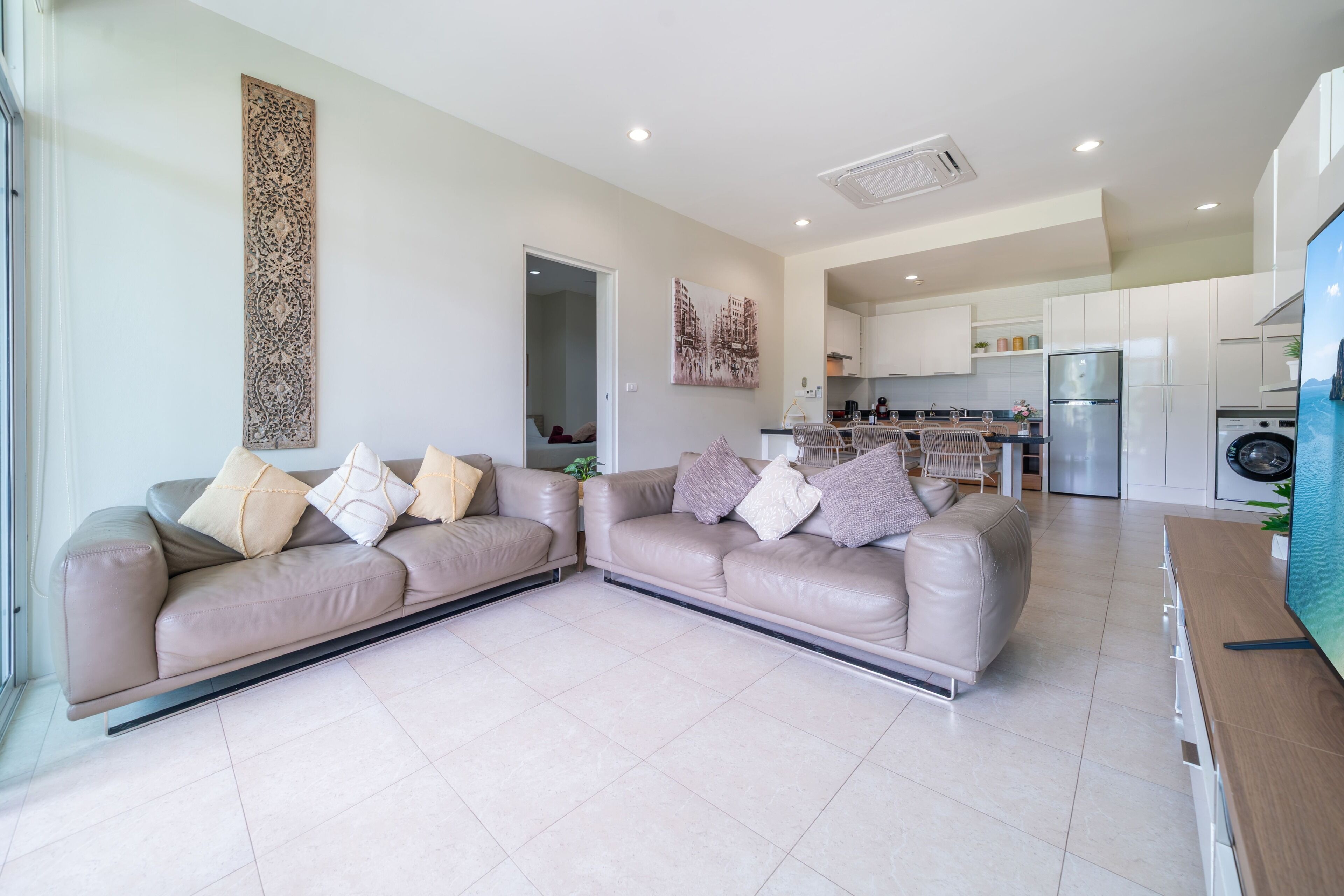 A modern living room with a sofa set, a dining area, and a kitchen.