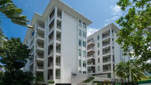 A multi-story building with a flat facade, balconies, and a sign indicating 'Palm' on the ground floor.